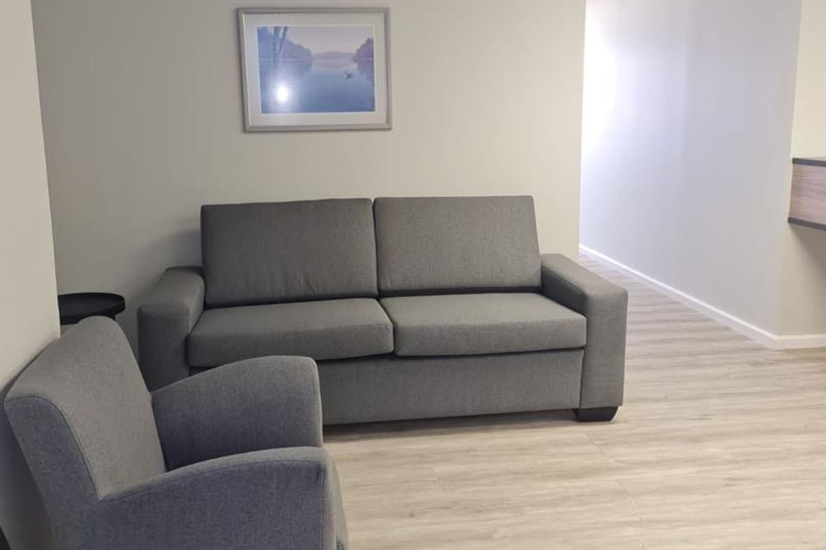 A professional office waiting area featuring neutral walls, modern laminate flooring, and a suspended ceiling with recessed lighting.