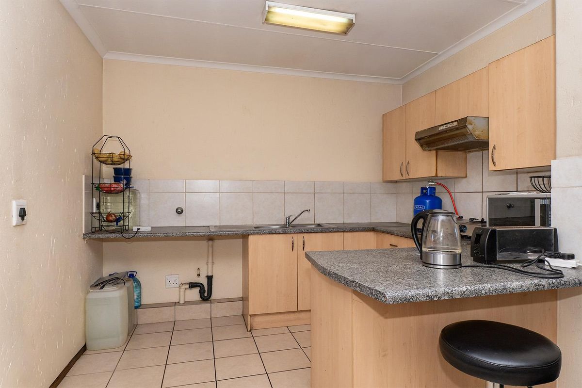 A functional kitchen featuring light wood cabinetry, granite-look countertops, tiled flooring, and a built-in extractor fan, offering a practical layout for daily use.