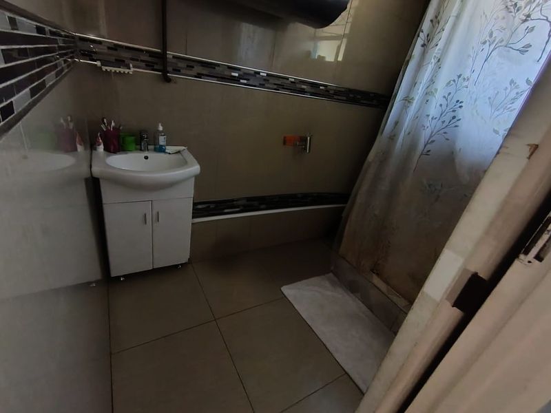 A functional bathroom featuring tiled walls and flooring, a vanity cabinet with a basin, and a shower area with a curtain.