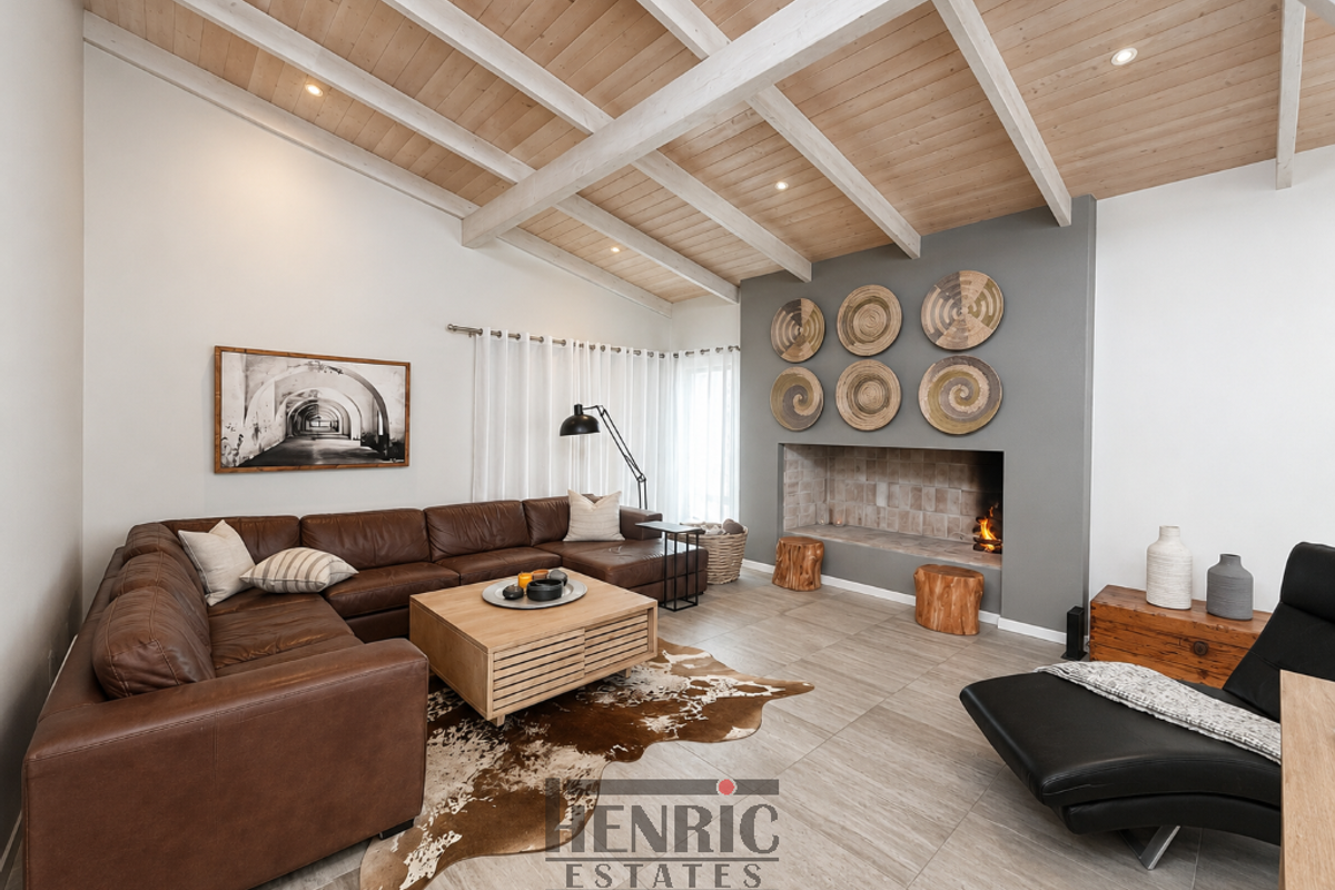 Spacious living room featuring a vaulted timber-beamed ceiling, tiled flooring, and a built-in fireplace with a feature grey wall.