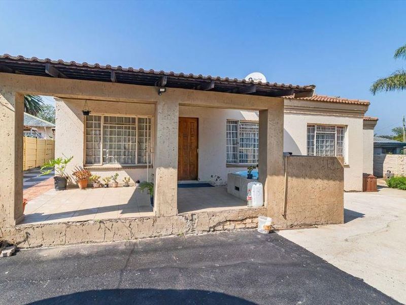 Front exterior view of the house featuring a covered patio area, tiled flooring, and a concrete driveway.