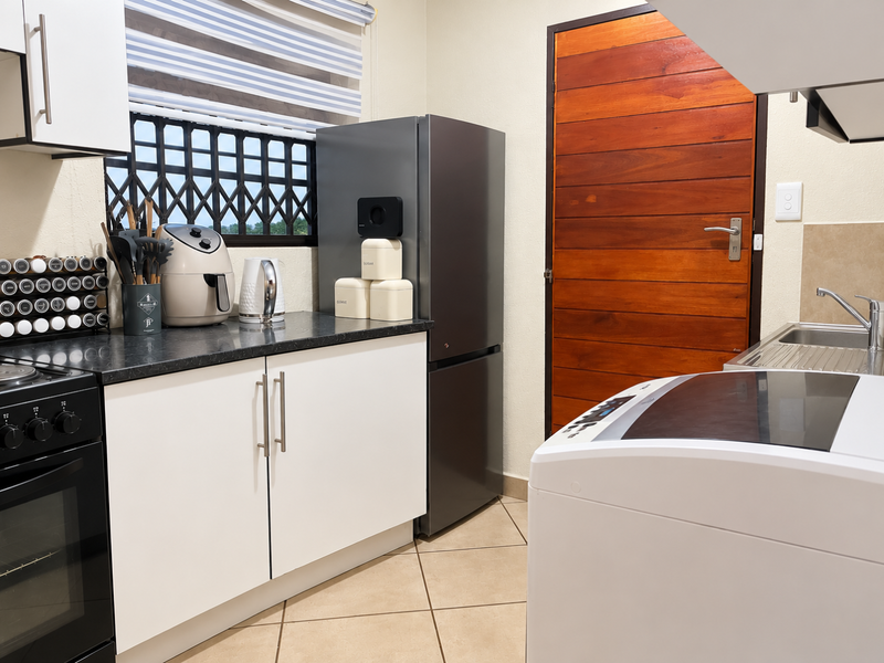 A functional kitchen featuring white cabinetry, dark laminate countertops, a built-in oven, and a stainless steel sink with tiled flooring.