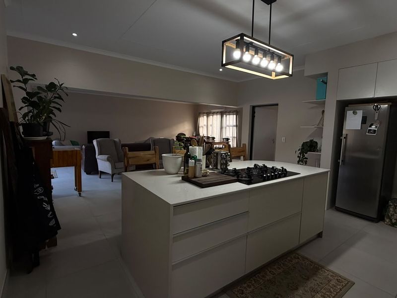 Spacious open-plan kitchen and living area featuring a central island with a gas cooktop, modern cabinetry, and contemporary pendant lighting.