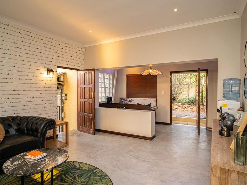 A living room featuring polished concrete floors, recessed lighting, and a half-height partition wall leading to an outdoor access point.