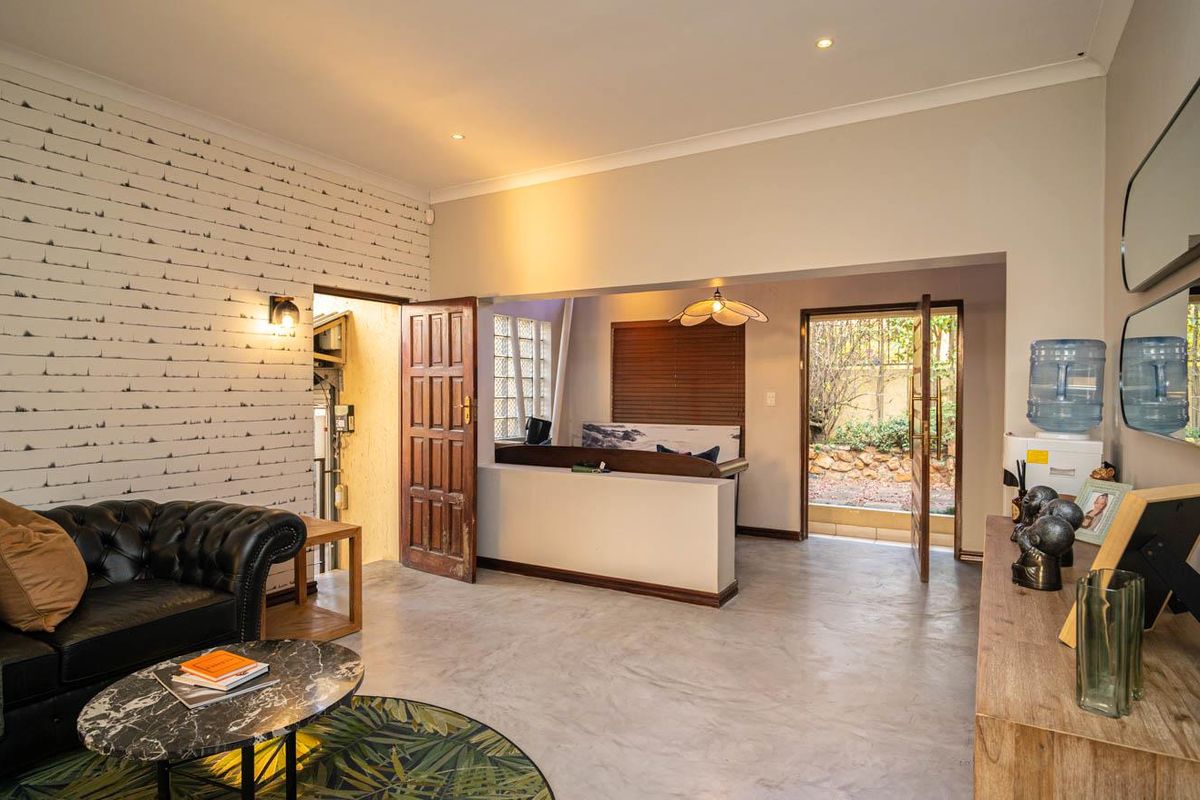 A living room featuring polished concrete floors, recessed lighting, and a half-height partition wall leading to an outdoor access point.