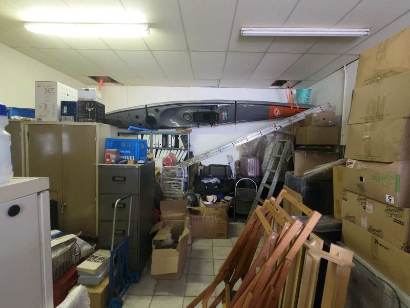 A utility or storage space featuring a suspended ceiling with fluorescent lighting and tiled flooring, currently used for general storage.