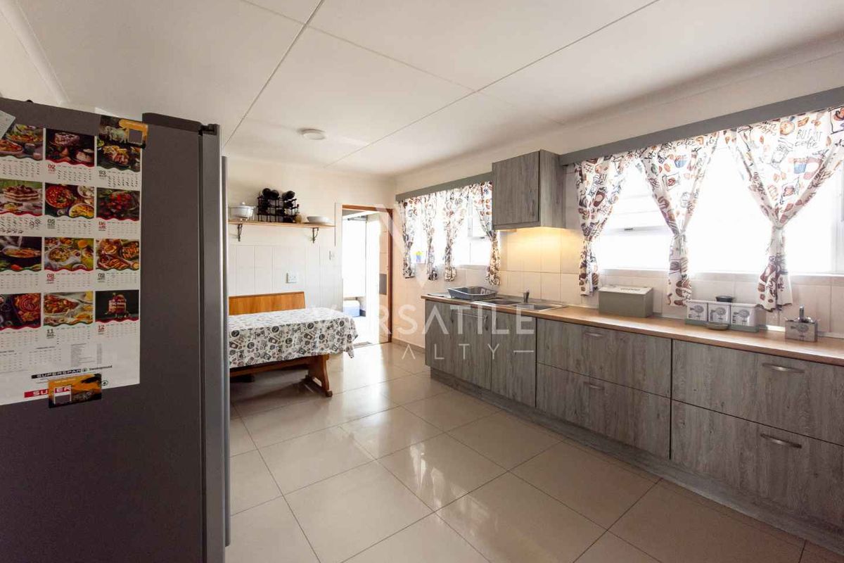A functional kitchen featuring wood-look cabinetry, tiled flooring, and a built-in sink area with ample natural light.