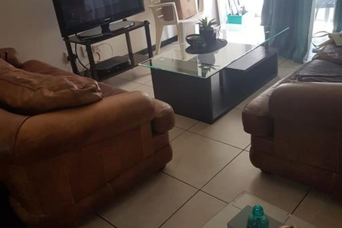 A living room area featuring tiled flooring and direct access to an outdoor balcony through a sliding glass door.