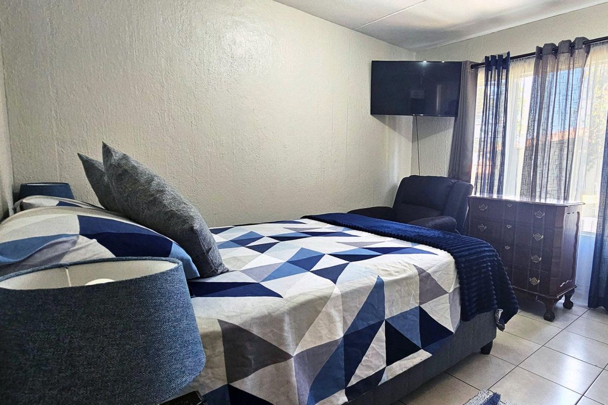 A bedroom featuring tiled flooring and a wall-mounted television.