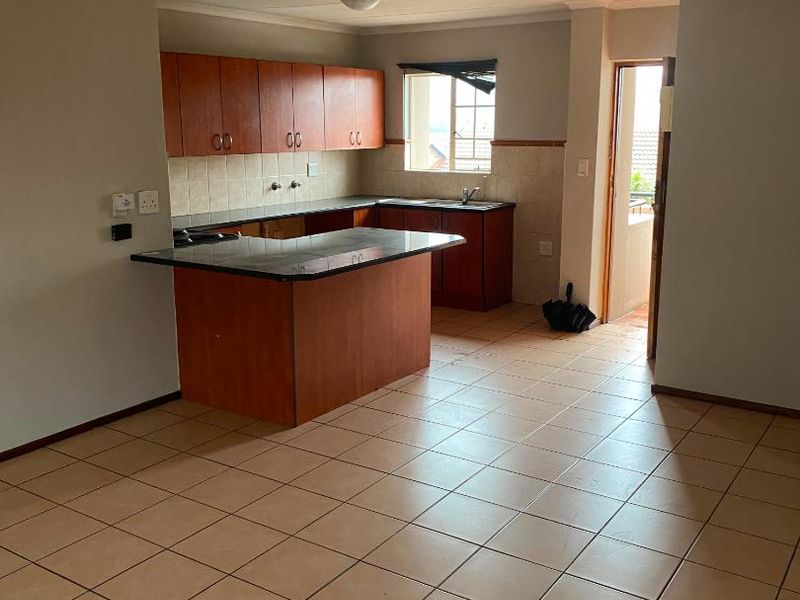 Open-plan kitchen and living area featuring tiled flooring, built-in wooden cabinetry, granite countertops, and direct access to an outdoor space.