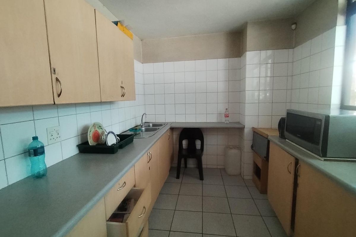 A functional office kitchenette featuring laminate cabinetry, tiled splashbacks, a double-basin sink, and tiled flooring.