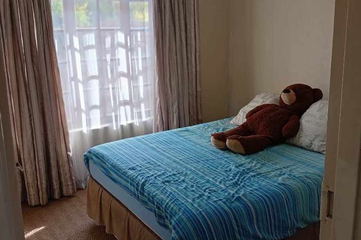 A standard bedroom featuring carpeted flooring and a window with curtains, providing natural light.