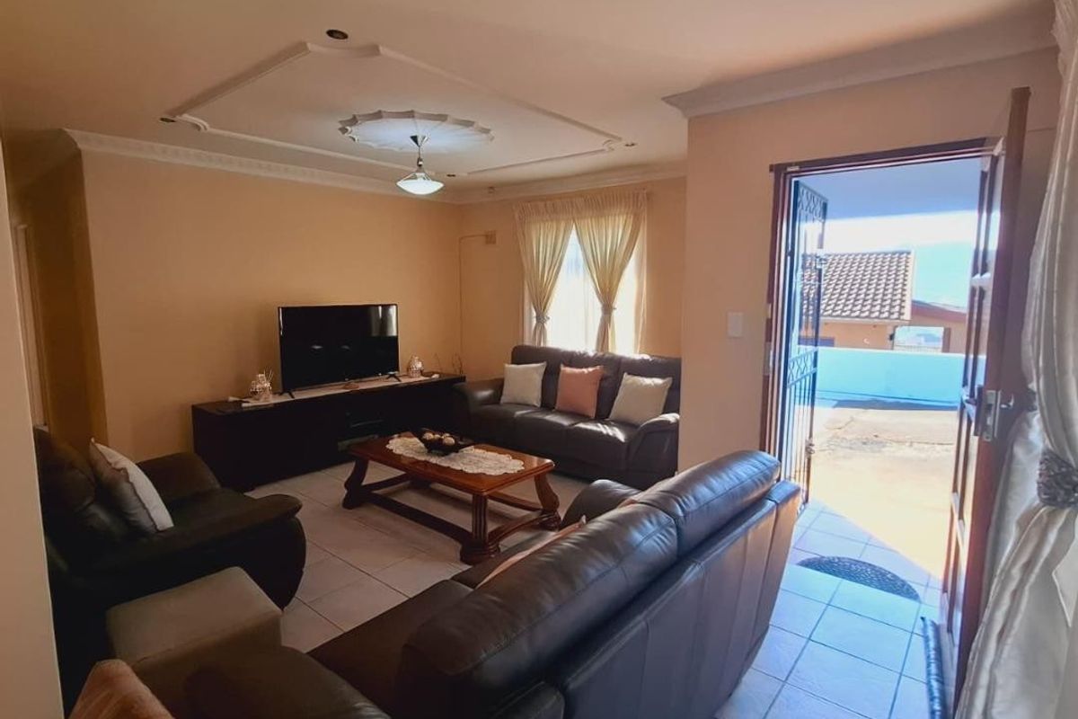 A comfortable living room featuring tiled flooring, decorative ceiling detailing, and direct access to an outdoor area through a sliding door.