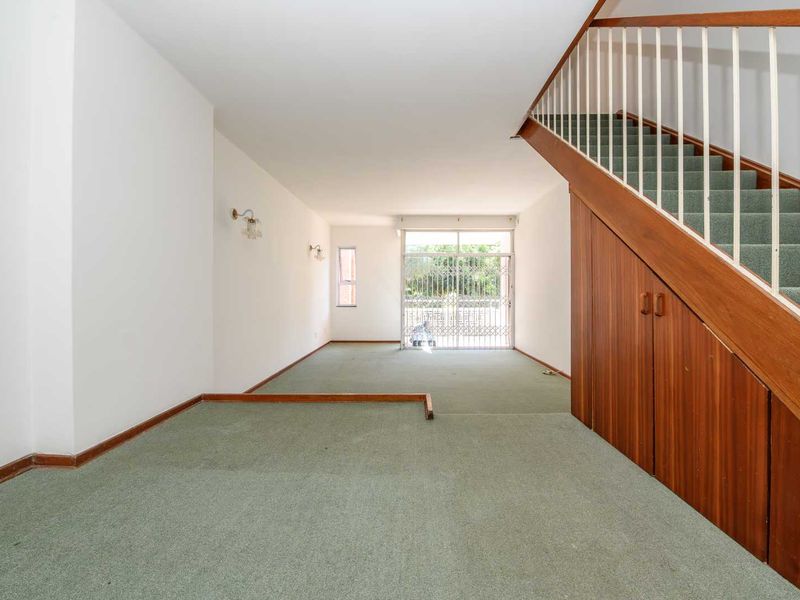 Spacious open-plan living area featuring a staircase with integrated under-stair storage cabinetry and access to an outdoor patio through a sliding glass door.