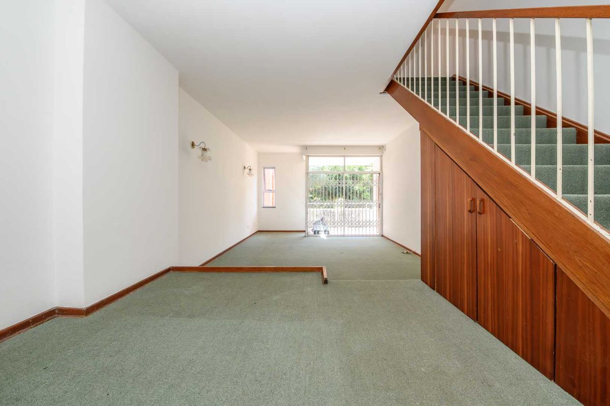 Spacious open-plan living area featuring a staircase with integrated under-stair storage cabinetry and access to an outdoor patio through a sliding glass door.