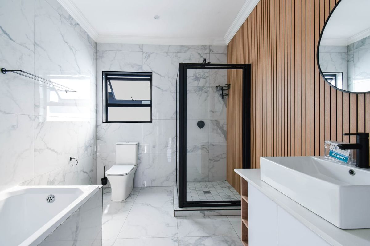 Modern bathroom featuring marble-look wall and floor tiles, a glass-enclosed shower, a sleek vanity with a vessel sink, and a contemporary bathtub.
