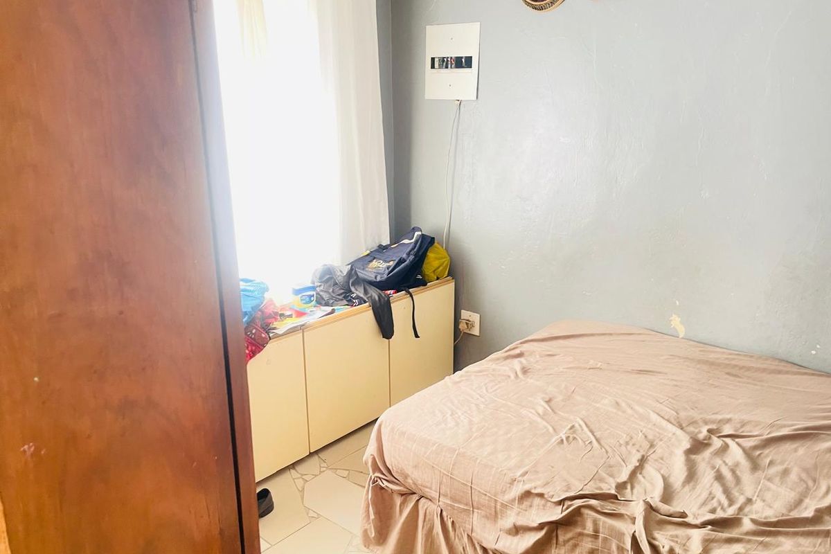 A bedroom featuring tiled flooring, a built-in storage unit, and a wall-mounted electrical distribution board.