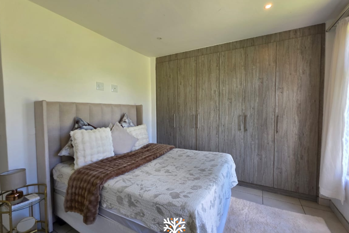 A well-maintained bedroom featuring extensive built-in wooden cabinetry and tiled flooring, offering ample storage space and a clean, neutral aesthetic.