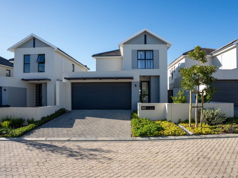 Modern double-story townhouse featuring a paved driveway, integrated double garage, and clean architectural lines with a well-maintained front garden.
