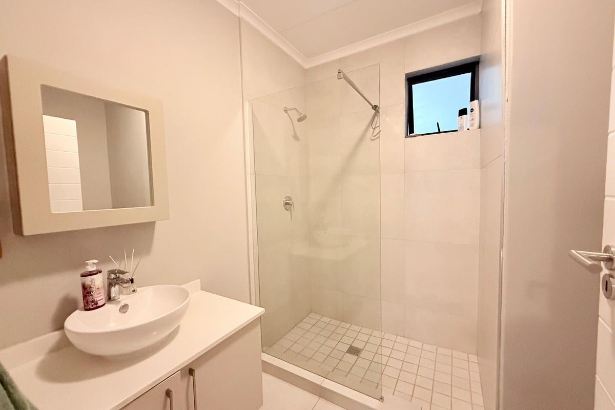 Modern bathroom featuring a glass-enclosed walk-in shower, a contemporary vessel sink vanity, and neutral floor-to-ceiling tiling.