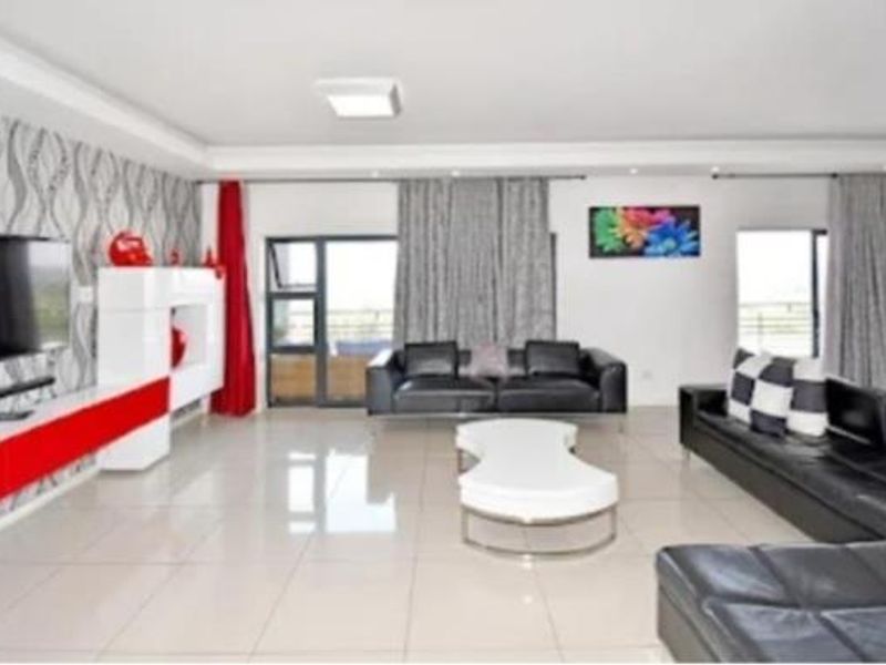 Spacious living room featuring large format floor tiles, recessed ceiling lighting, and sliding glass doors providing access to an outdoor area.