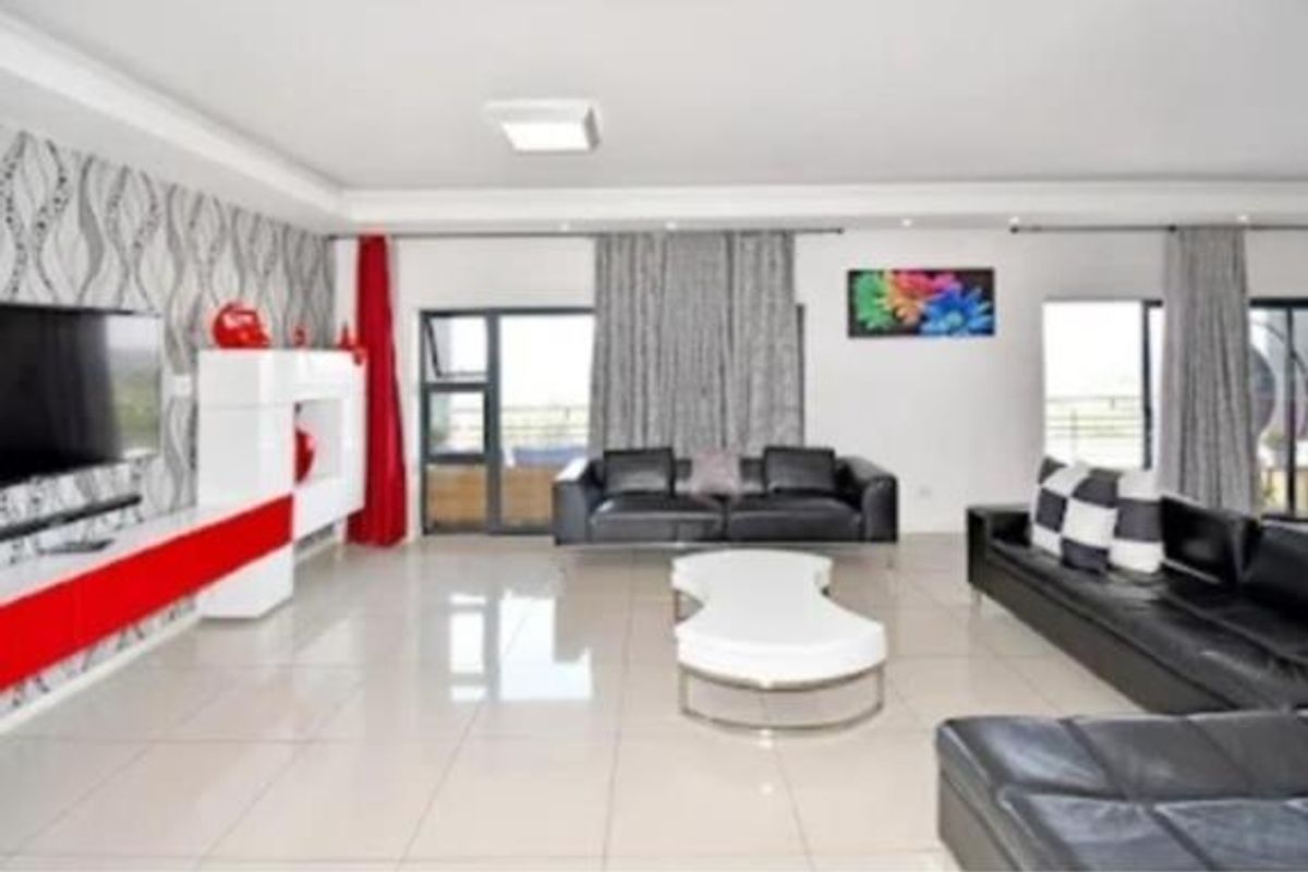 Spacious living room featuring large format floor tiles, recessed ceiling lighting, and sliding glass doors providing access to an outdoor area.