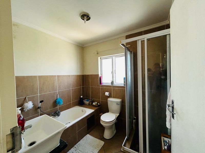 A functional bathroom featuring a bathtub, separate shower enclosure, toilet, and basin with tiled finishes.