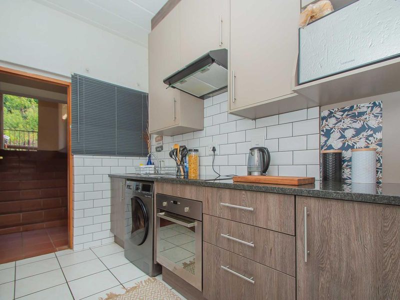 Modern kitchen featuring wood-grain cabinetry, subway tile backsplash, stone countertops, and integrated appliances, offering a clean and functional cooking space.