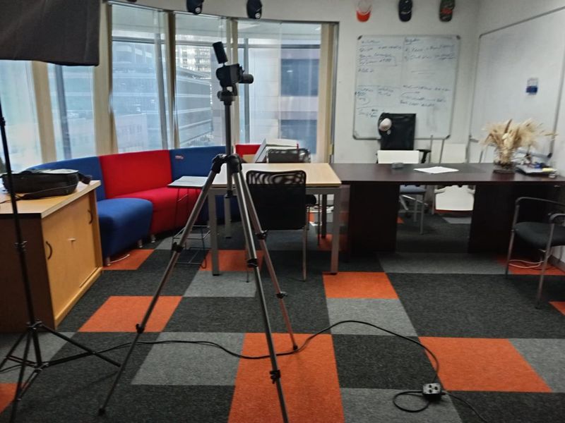 A functional office space featuring large windows, carpet tile flooring, and a wall-mounted whiteboard, suitable for a collaborative work environment.