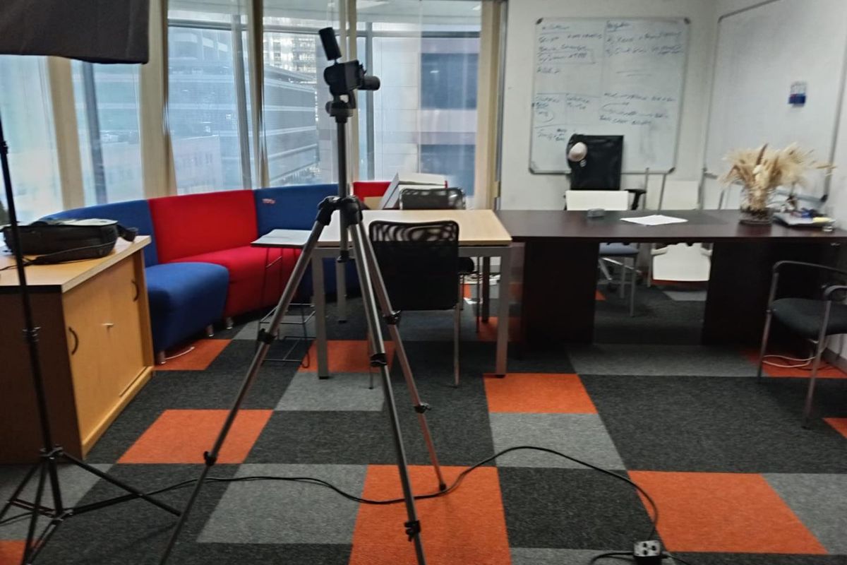 A functional office space featuring large windows, carpet tile flooring, and a wall-mounted whiteboard, suitable for a collaborative work environment.
