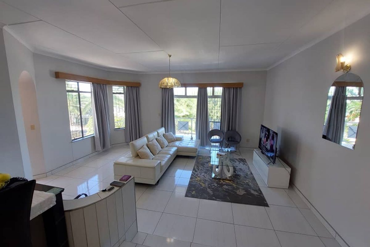 Spacious living room featuring large windows, tiled flooring, and a neutral color palette, offering a bright and open atmosphere.