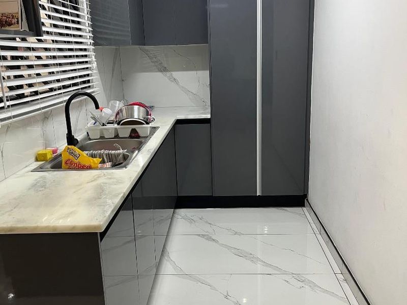 Modern scullery featuring high-gloss grey cabinetry, marble-effect stone countertops, matching floor tiles, and a sleek black mixer tap.
