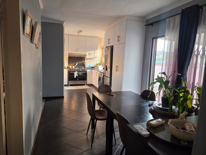 Open-plan kitchen and dining area featuring tiled floors, modern white cabinetry, and a gas stove, with direct access to an outdoor space.