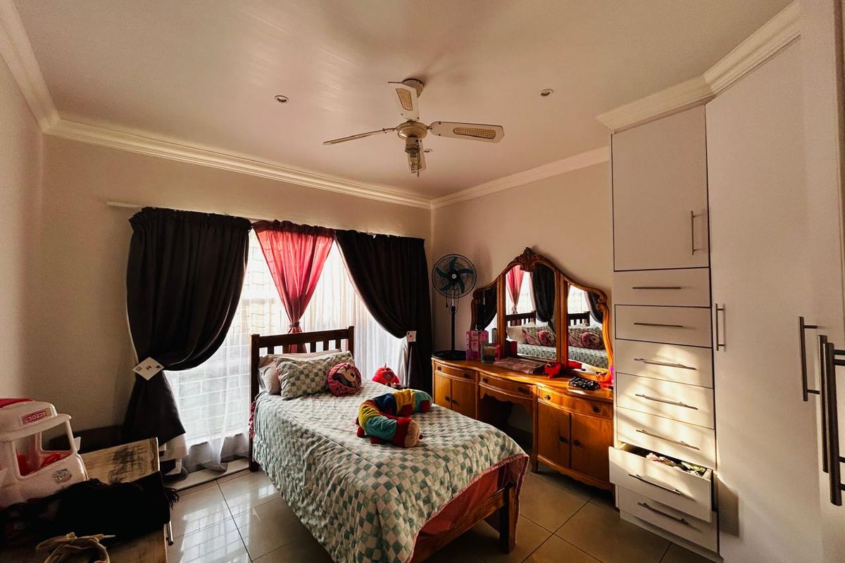 A well-lit bedroom featuring tiled flooring, a ceiling fan, and built-in floor-to-ceiling cabinetry with ample storage space.