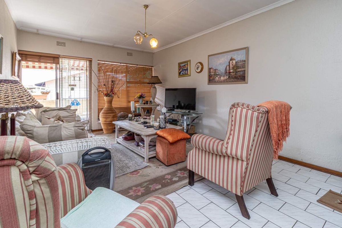 A comfortable living room featuring tiled flooring, a ceiling light fixture, and sliding glass doors providing access to an outdoor patio area.