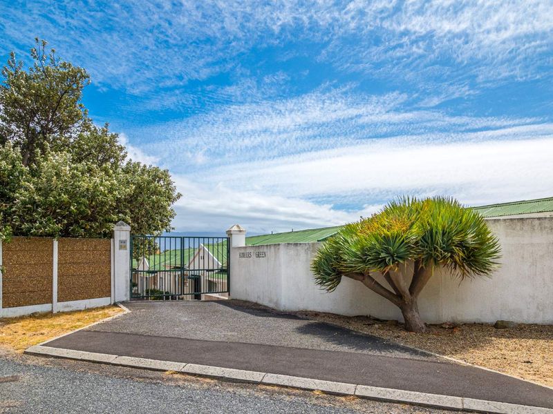 Street view of the entrance to Bunkers Green, featuring a secure metal gate, boundary wall, and paved driveway access.