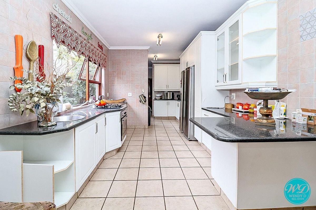 Spacious kitchen featuring white cabinetry, dark granite countertops, tiled flooring, and a built-in oven with hob, offering ample workspace and storage.