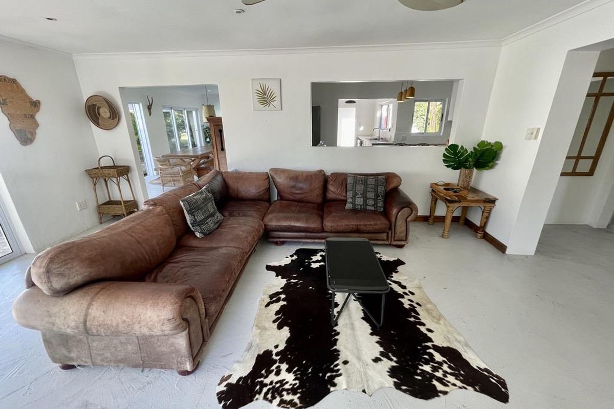 Spacious living room featuring a ceiling fan, recessed lighting, and a convenient pass-through window connecting to the kitchen area.