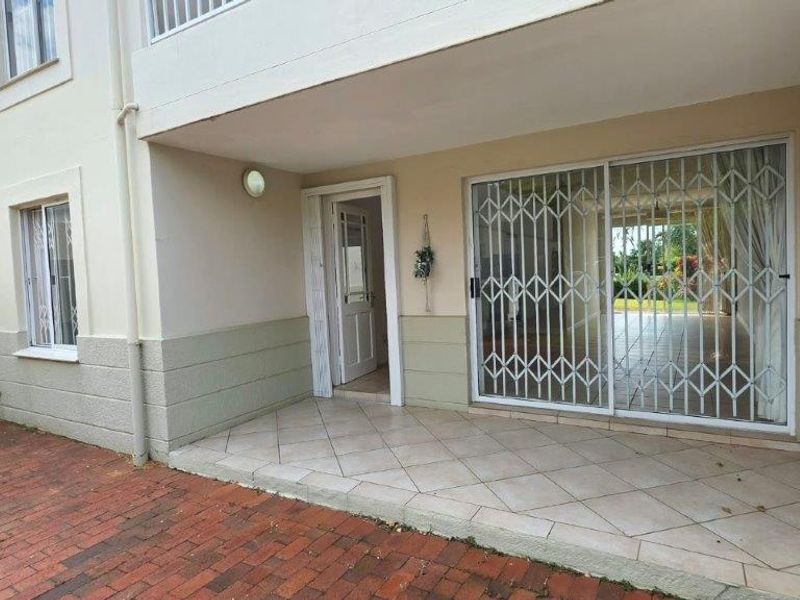 Covered patio area featuring tiled flooring, a sliding security gate, and direct access to the interior living space.