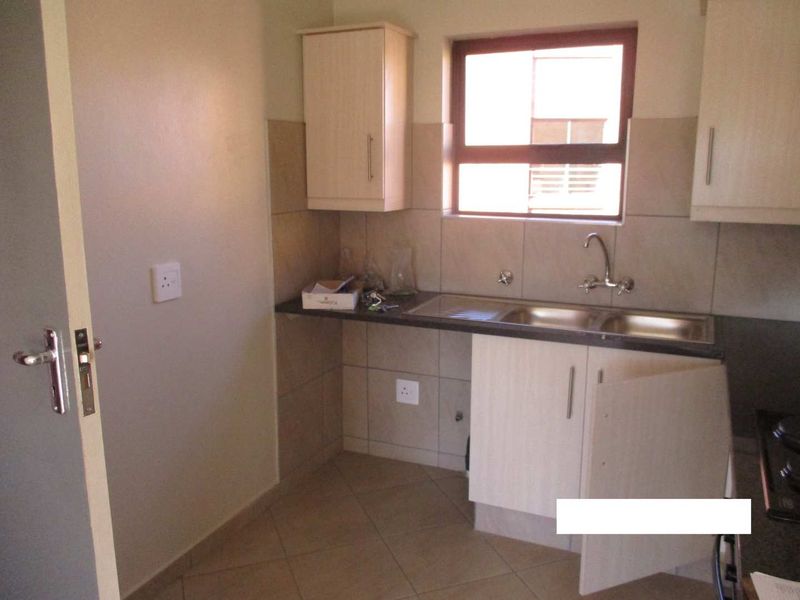 A functional kitchen area featuring laminate cabinetry, a double sink with mixer tap, tiled backsplash, and tiled flooring.