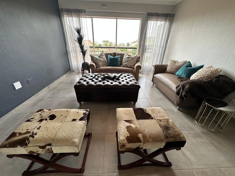 A well-lit living room featuring large sliding glass doors that provide natural light and access to an outdoor balcony area.