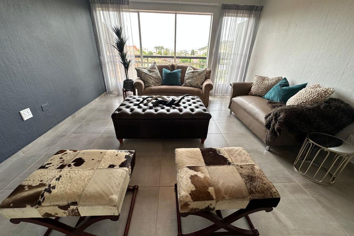 A well-lit living room featuring large sliding glass doors that provide natural light and access to an outdoor balcony area.