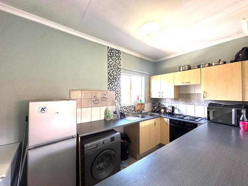 Functional kitchen featuring laminate cabinetry, tiled backsplash, built-in oven, electric hob, and stainless steel sink with ample countertop workspace.