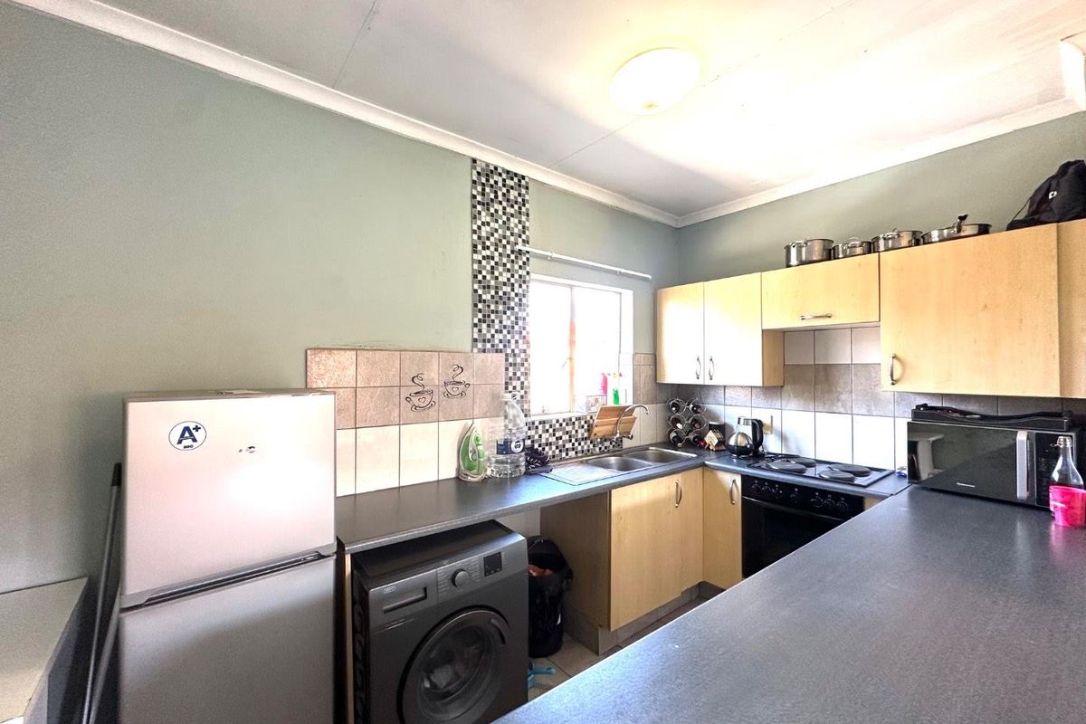 Functional kitchen featuring laminate cabinetry, tiled backsplash, built-in oven, electric hob, and stainless steel sink with ample countertop workspace.