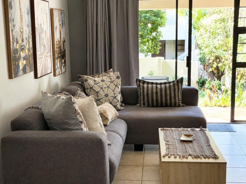 A comfortable living room featuring tiled flooring and a large sliding glass door that provides direct access to the outdoor patio area.