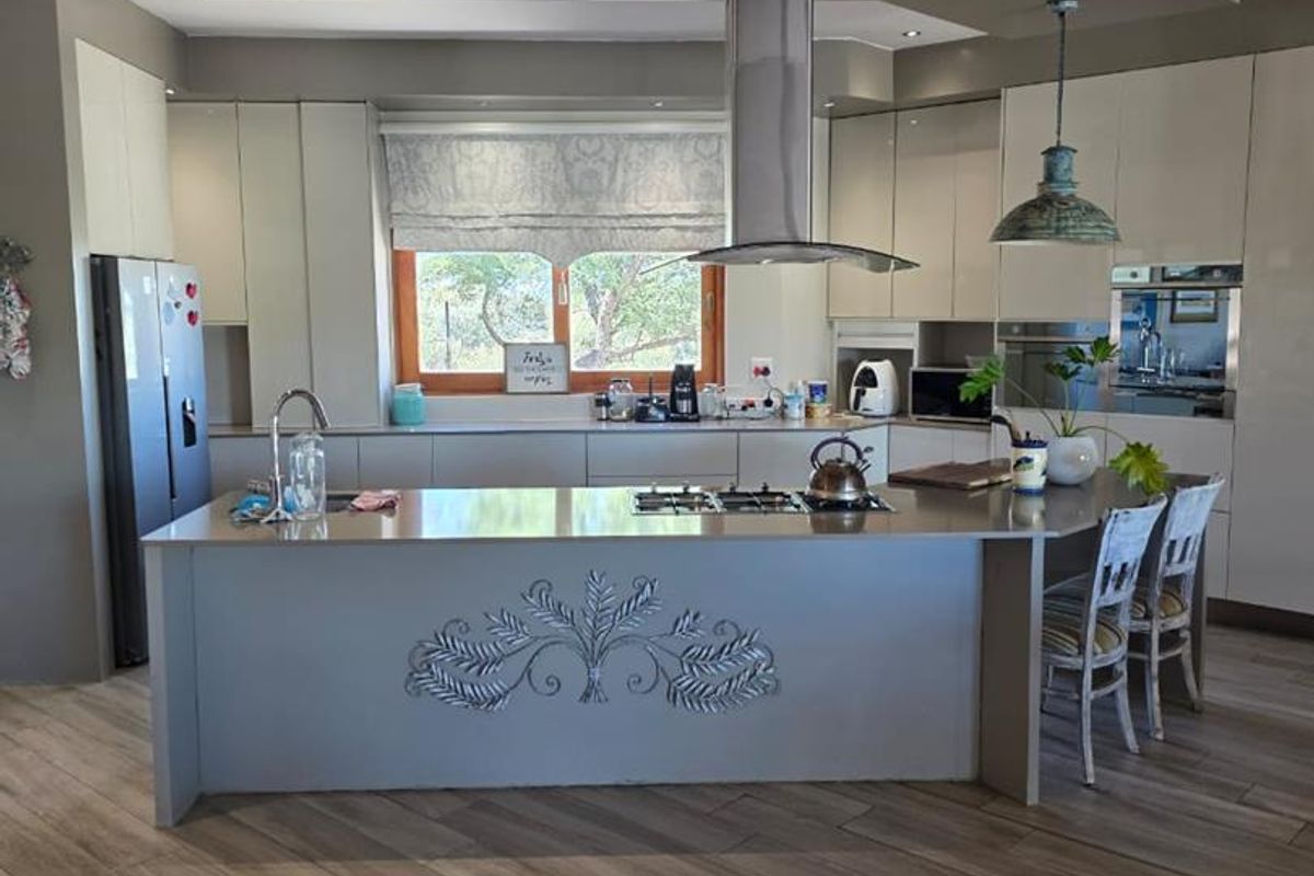 Modern kitchen featuring a large central island with a built-in gas hob, stainless steel extractor fan, and sleek cabinetry with integrated appliances.