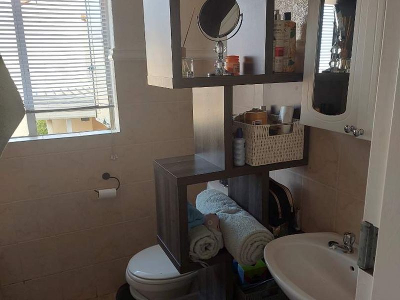 Compact bathroom featuring a pedestal basin, toilet, tiled finishes, and a medicine cabinet, requiring minor maintenance and cosmetic updates.