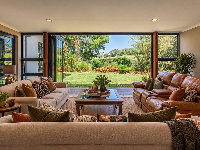 Spacious living room featuring large bi-fold doors that open onto a landscaped garden and timber deck, creating a seamless indoor-outdoor flow.