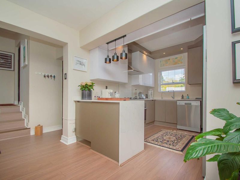 Modern kitchen featuring sleek cabinetry, stone countertops, and integrated lighting, seamlessly flowing into the adjacent living area with durable laminate flooring.