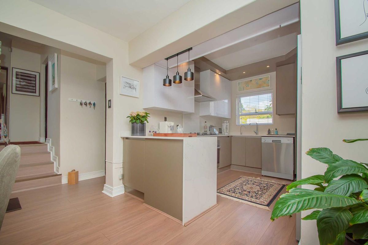 Modern kitchen featuring sleek cabinetry, stone countertops, and integrated lighting, seamlessly flowing into the adjacent living area with durable laminate flooring.